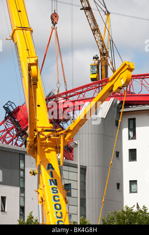 Turmdrehkran brach gefallenen auf Dach der Wohnblock wird von einem anderen Kran abgehoben Stockfoto