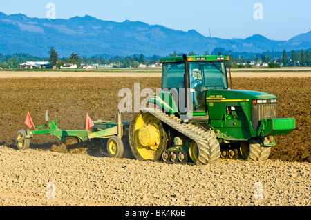 John Deere Traktor Pflügen mit reversiblen Pflug auf das Feld bereiten für die Bepflanzung im Frühjahr im Skagit County, Washington Stockfoto