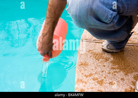 Man gießt benötigten Chemikalien in Swimming Pool. Stockfoto