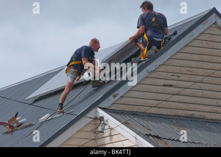 Arbeiter, die Installation von Sonnenkollektoren auf dem Dach in Hobart Tasmanien Australien Stockfoto