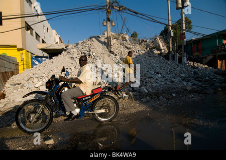 Die Menschen kommen an einem Gebäude vorbei, das in Port-au-Prince nach einem Erdbeben der Stärke 7,0 am 12. Januar 2010 einstürzte Stockfoto