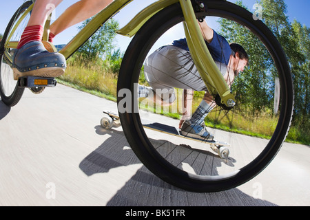 Frau auf dem Fahrrad und Mann reitet eine Skateboard auf ein Fahrrad Weg, Steamboat Springs, Routt County, Colorado, USA Stockfoto