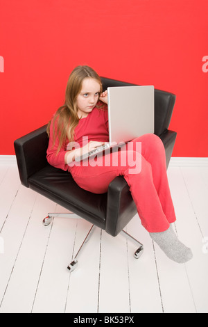 Mädchen sitzen im Stuhl mit Laptop-Computer Stockfoto