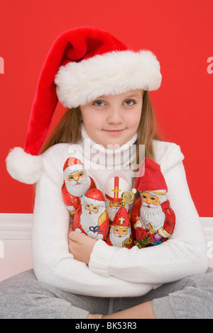 Porträt von Mädchen hält Santa Ornamente tragen Weihnachtsmütze Stockfoto