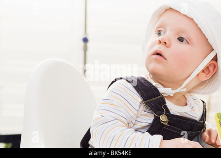 Junge sitzt im Hochstuhl Blick überrascht Stockfoto