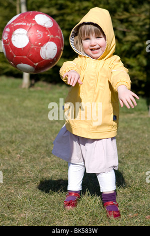 Kinder spielen im Freien in einem Feld mit Rasen in der Sonne mit einem ball Stockfoto