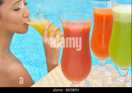 Junge Frau in einem Schwimmbad schlürfen eine eine Auswahl an Fruchtsäften Stockfoto