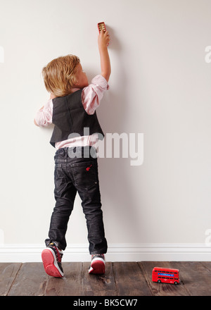 Kleiner Junge spielt mit Spielzeugautos auf Wand Stockfoto