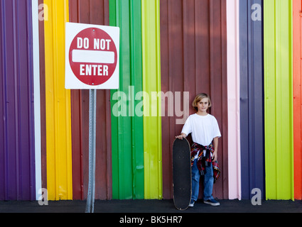 Junge mit Skateboard vor bunten Wand Stockfoto