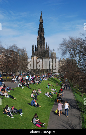 Menschen genießen die Frühlingssonne durch das Scott Monument in Edinburgh Princes Street Gardens. Stockfoto