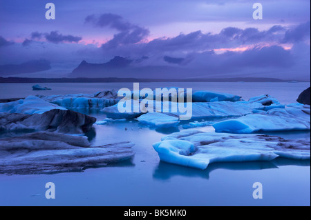 Eisberge in der Gletscherlagune Jökulsárlón, Dusk, Oraefajokull (Vatnajökull) Gletscher in der Ferne, Island Stockfoto