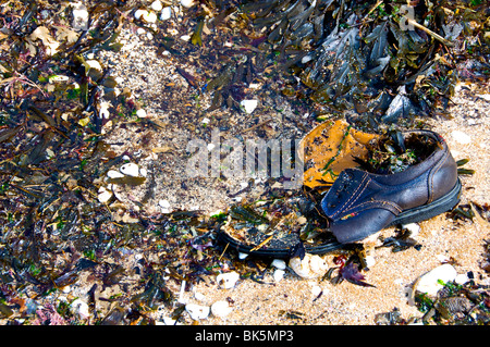 Ein einzelner Schuh auf Broadstairs Strand, umgeben von Algen, Kieselsteine und Muscheln. Stockfoto