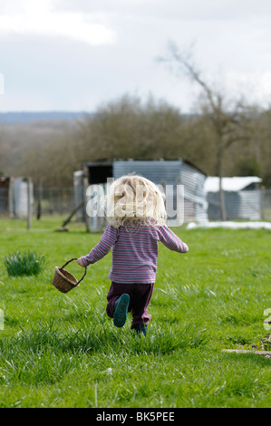 Stock Foto eines 4-jährigen Kindes laufen im Garten, während einen Korb zu tragen. Stockfoto