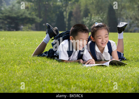 Grundschüler lesen auf dem Rasen Stockfoto