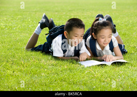 Grundschüler lesen auf dem Rasen Stockfoto