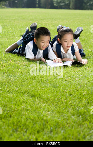 Grundschüler lesen auf dem Rasen Stockfoto