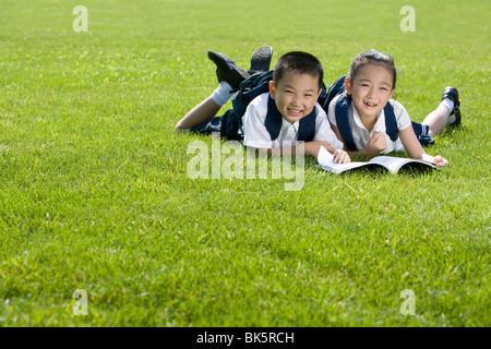 Grundschüler lesen auf dem Rasen Stockfoto
