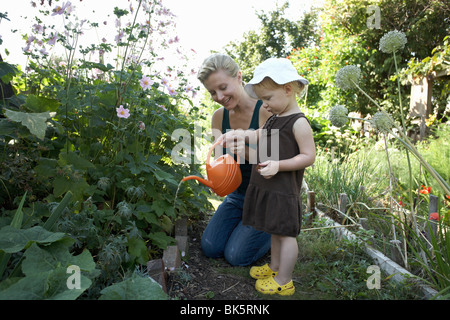 Mutter und Tochter im Garten Bewässerung Pflanzen Stockfoto