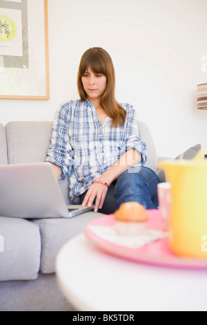 Frau sitzt auf dem Sofa mit Laptop-Computer Stockfoto