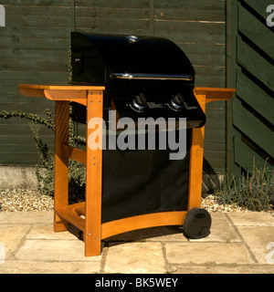 Stand-alone Gasgrill, Grill, Grill, in einer Gartenanlage auf einer Terrasse mit einem grünen Zaun Stockfoto