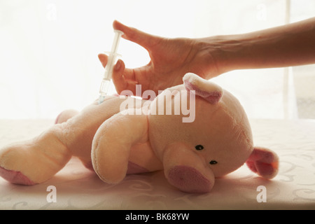 Spielzeug-Schwein-Arzt-Hand mit Spritze. Stockfoto