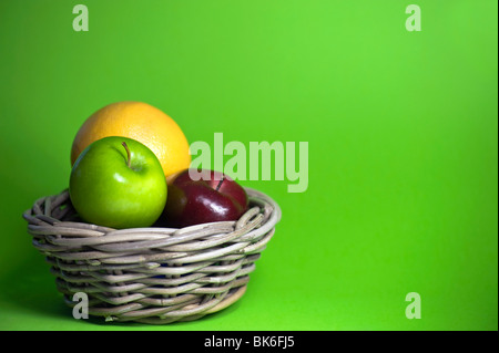 Äpfel im Korb, vor grünem Hintergrund Stockfoto