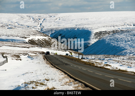 Ein Auto auf der A57 Snake Pass Straße im Winter, in der Nähe von Glossop, Peak District, Derbyshire, England, UK Stockfoto