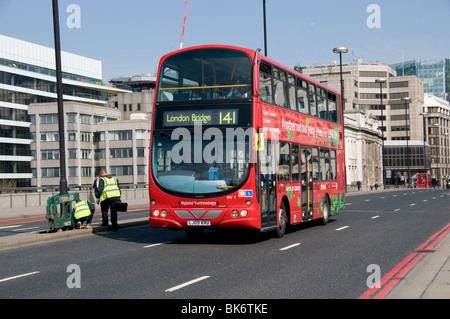 Eine Hybrid London Bus überquert London Brücke Richtung London Bridge Station an einem sonnigen Morgen Stockfoto