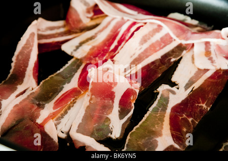 Speckscheiben Speck, Roh und durchwachsener Speck - gekocht / gebraten in der Pfanne. Nahaufnahme. Stockfoto