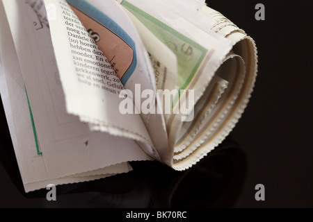 Zeitung mit Gummiband auf schwarz aufgerollt Stockfoto