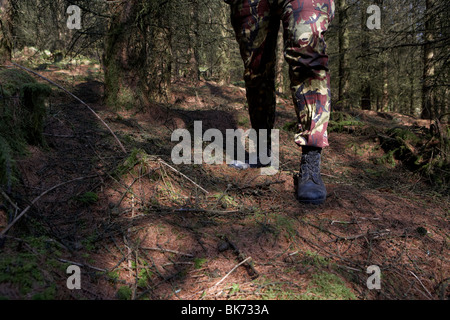 Mann trägt Tarnung Kampf Hose und Stiefel stehen Bewachung in einem Wald im Vereinigten Königreich Stockfoto