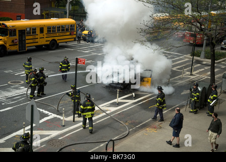 Mitglieder der FDNY löschen ein Taxi, das an der Ninth Avenue im New Yorker Stadtteil Chelsea Feuer gefangen hat Stockfoto