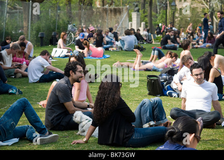 New Yorker und Besucher nutzen das warme Frühlingswetter auf einer Grünfläche im Washington Square Park in New York Stockfoto