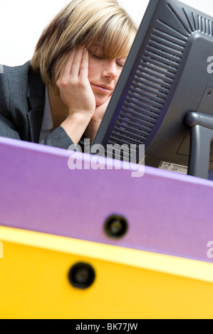 müde weibliche Büroangestellte schlafen am Schreibtisch Stockfoto