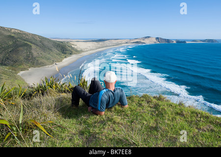 Northland, Cape Lorena, Mann Verlegung auf Rasen, mit Blick auf Strand Stockfoto