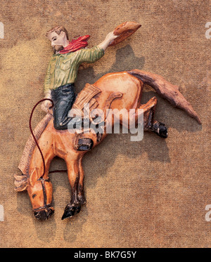 Cowboy Figur auf Rodeo Pony mit rotem Schal und Cowboy-Hut auf eine bemalte Leinwand Hintergrund. Stockfoto