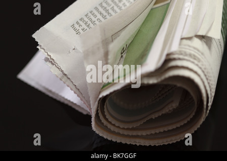 Zeitung mit Gummiband auf schwarz aufgerollt Stockfoto