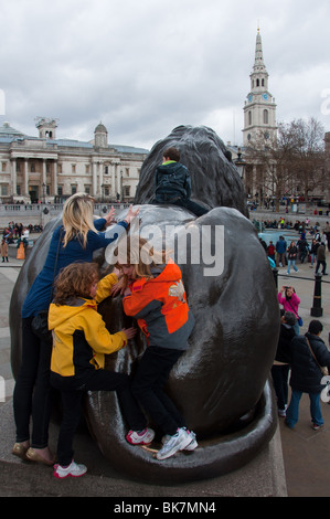 Eine Familie auf einem der Bronze Löwen am Trafalgar Square. Stockfoto