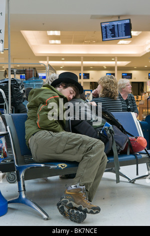 Mann schläft auf einem Flughafen Sitzplatz während ist, dass der Flug annulliert wird Stockfoto