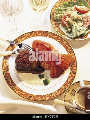 Hummer und petite Filet auf einen dekorativen Teller mit Salat und Glaswaren. Stockfoto