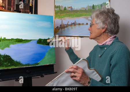 Senior Woman Gemälde Landschaft an Staffelei Stockfoto