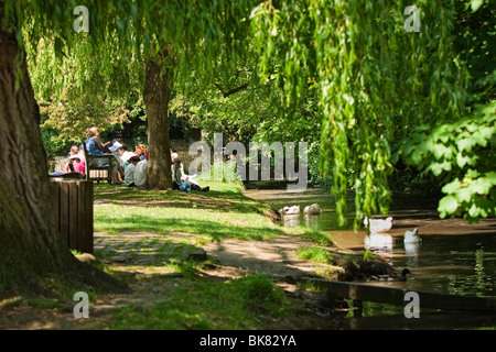 Schule Kinder füttern die Enten am Ufer des Flusses durch die Tillingbourne Fluss in Shere, Surrey, England, Großbritannien Stockfoto