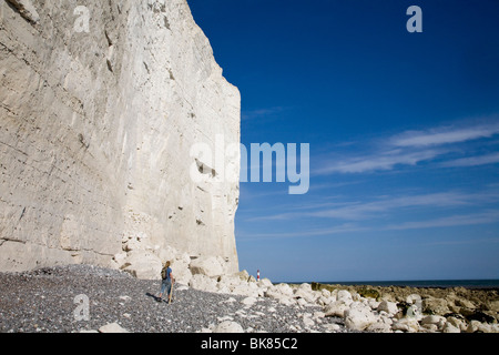 Ein Mann geht auf der Basis der Klippe, am Strand, in Richtung Beachy Head Leuchtturm. Stockfoto