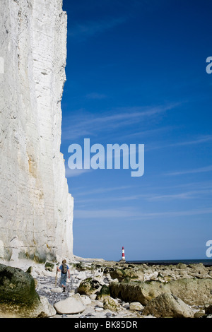 Ein Mann geht auf der Basis der Klippe, am Strand, in Richtung Beachy Head Leuchtturm. Stockfoto