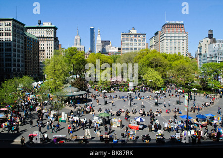 Union Square Frühling Wetter Menschenmassen New York City | NEW YORK, NY, Vereinigte Staaten – ein erhöhter Blick über den Union Square Park zeigt Menschenmassen an einem klaren Frühlingstag. Verkaufsstände säumen die plaza und das Empire State Building, die auf der Skyline sichtbar sind. Die 1856 geweihte Reiterstatue von George Washington steht in der Nähe des Parkzentrums. Der Union Square dient seit dem 19. Jahrhundert als öffentlicher Versammlungs- und Marktplatz. Stockfoto