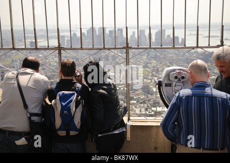 NEW YORK, New YORK, USA – Touristen bewundern die Aussicht von der Spitze des Empire State Building in New York City an einem klaren Frühlingstag. Die Aussichtsplattform bietet einen atemberaubenden Panoramablick auf Manhattan und darüber hinaus, was sie zu einer der bekanntesten Touristenattraktionen der Stadt macht. Stockfoto