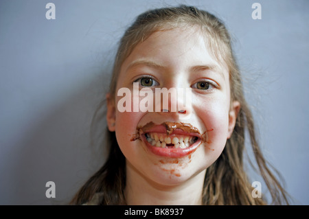 Junges Mädchen mit Gesicht und Mund bedeckt in Schokolade Stockfoto