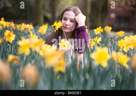 Ein junges Mädchen schaut nachdenklich in einem Feld von Narzissen. Stockfoto