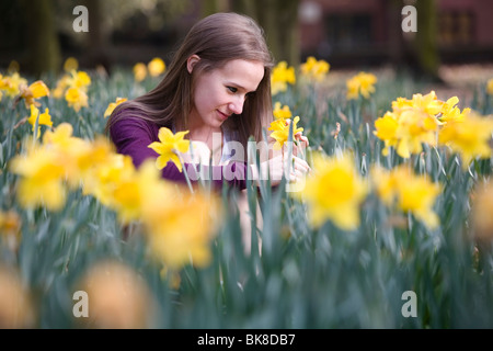 Ein junges Mädchen schaut nachdenklich in einem Feld von Narzissen. Stockfoto