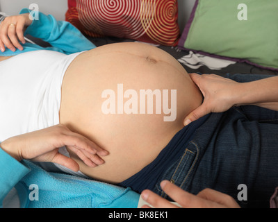 Nahaufnahme einer schwangeren Frau, kontrolliert durch eine Hebamme Stockfoto
